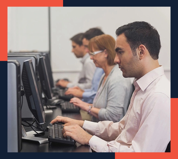 A group of people sitting at computers in front of each other.