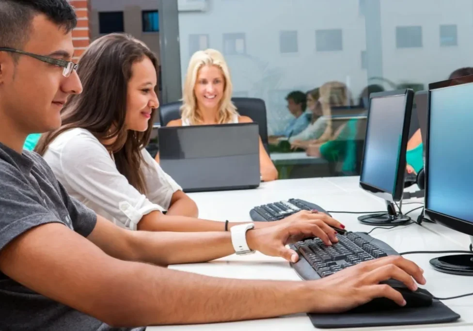 A group of people sitting at a table with computers.