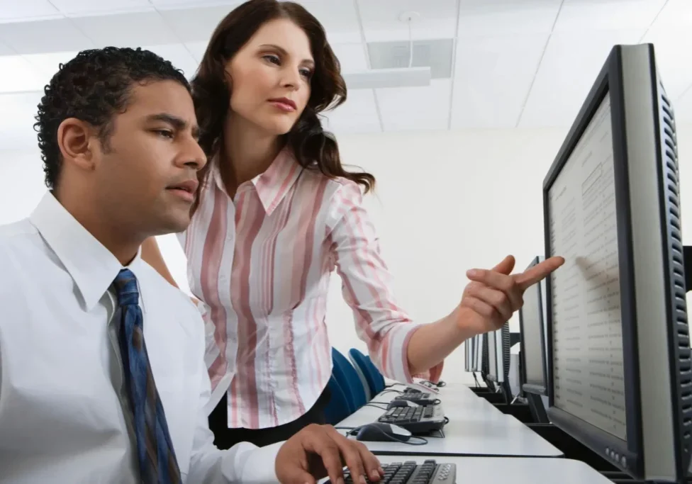 A woman pointing at something on the computer screen.